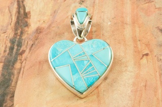 Genuine Sleeping Beauty Turquoise inlaid between ribbons of Sterling Silver. Beautiful Heart Pendant with precision inlay on the bale and pendant. Free 18" Sterling Silver Chain with Purchase of Pendant. Pendant Designed by Navajo Artist Calvin Begay. Signed. 